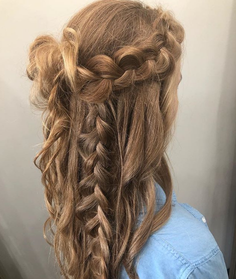 A woman with long hair is wearing a braided half up half down hairstyle.