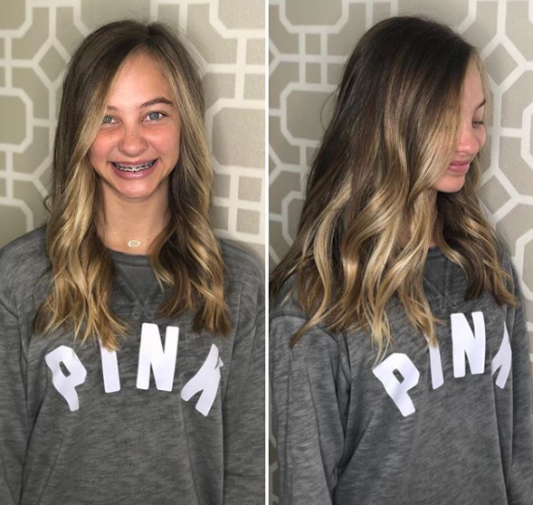 A girl wearing a pink sweater is smiling