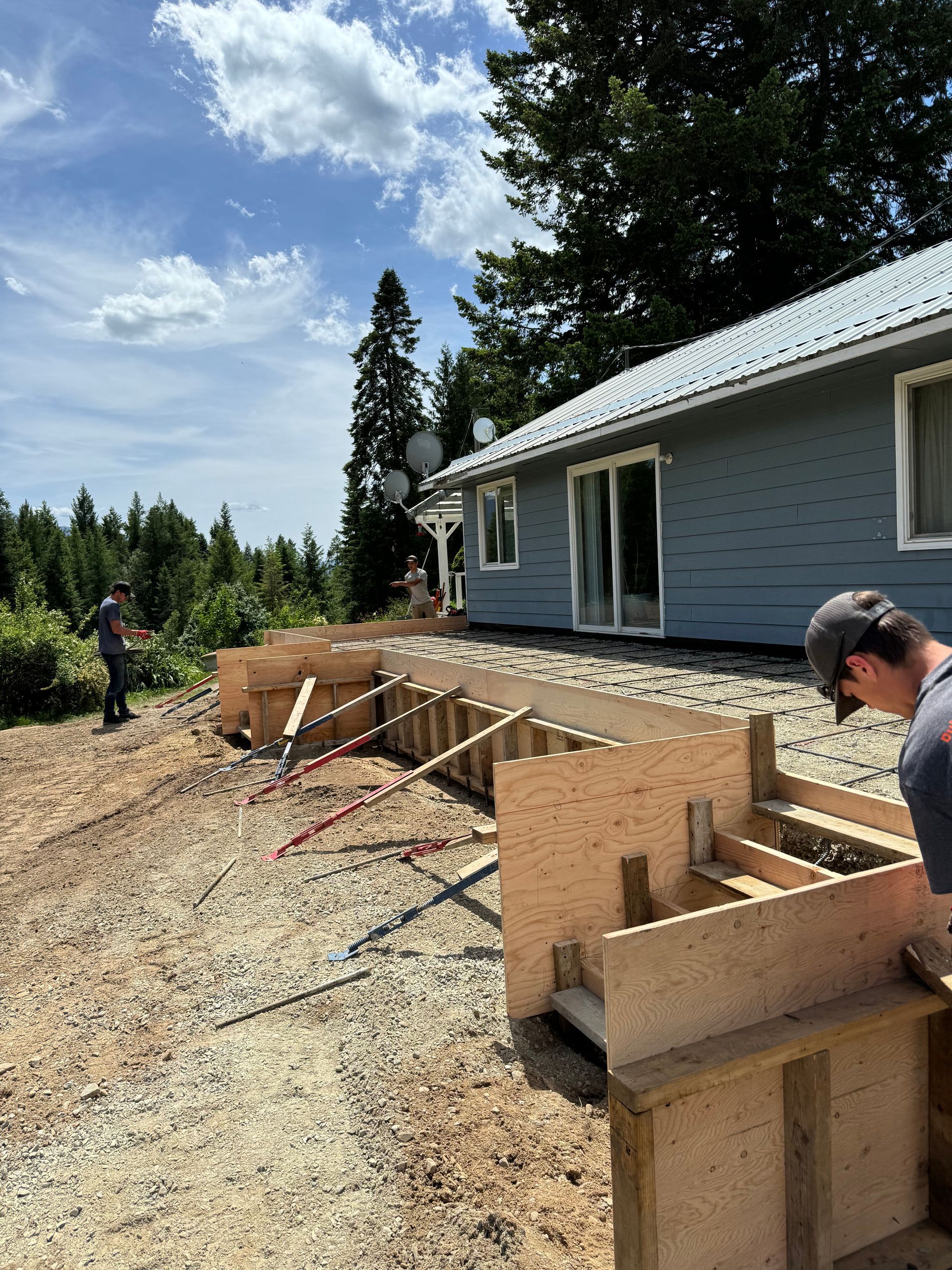 A man is working on a wooden structure in front of a house. Project done by Raise the Bar Construction