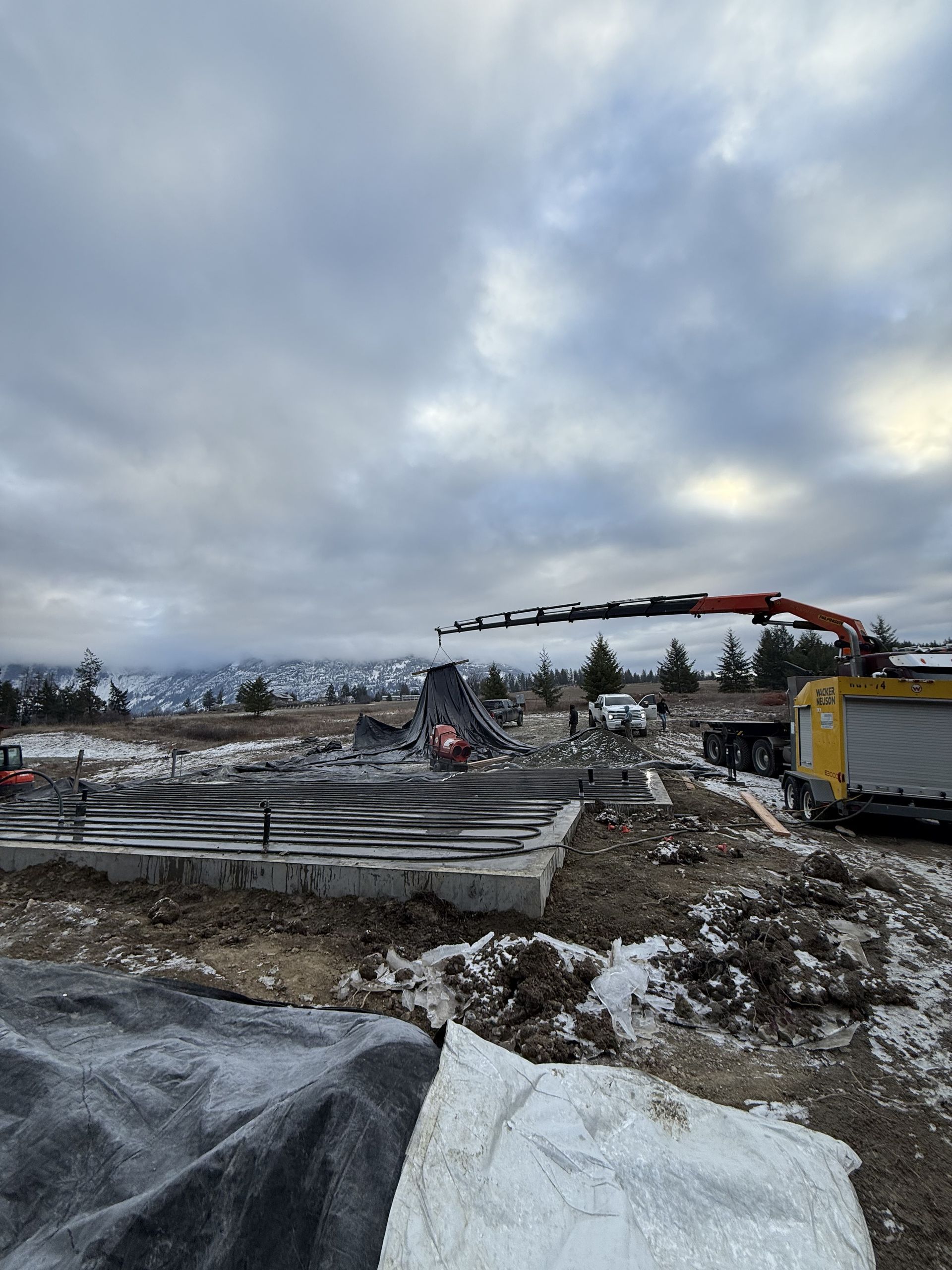 A crane is lifting a concrete slab in a construction site. Project done by Raise the Bar Construction