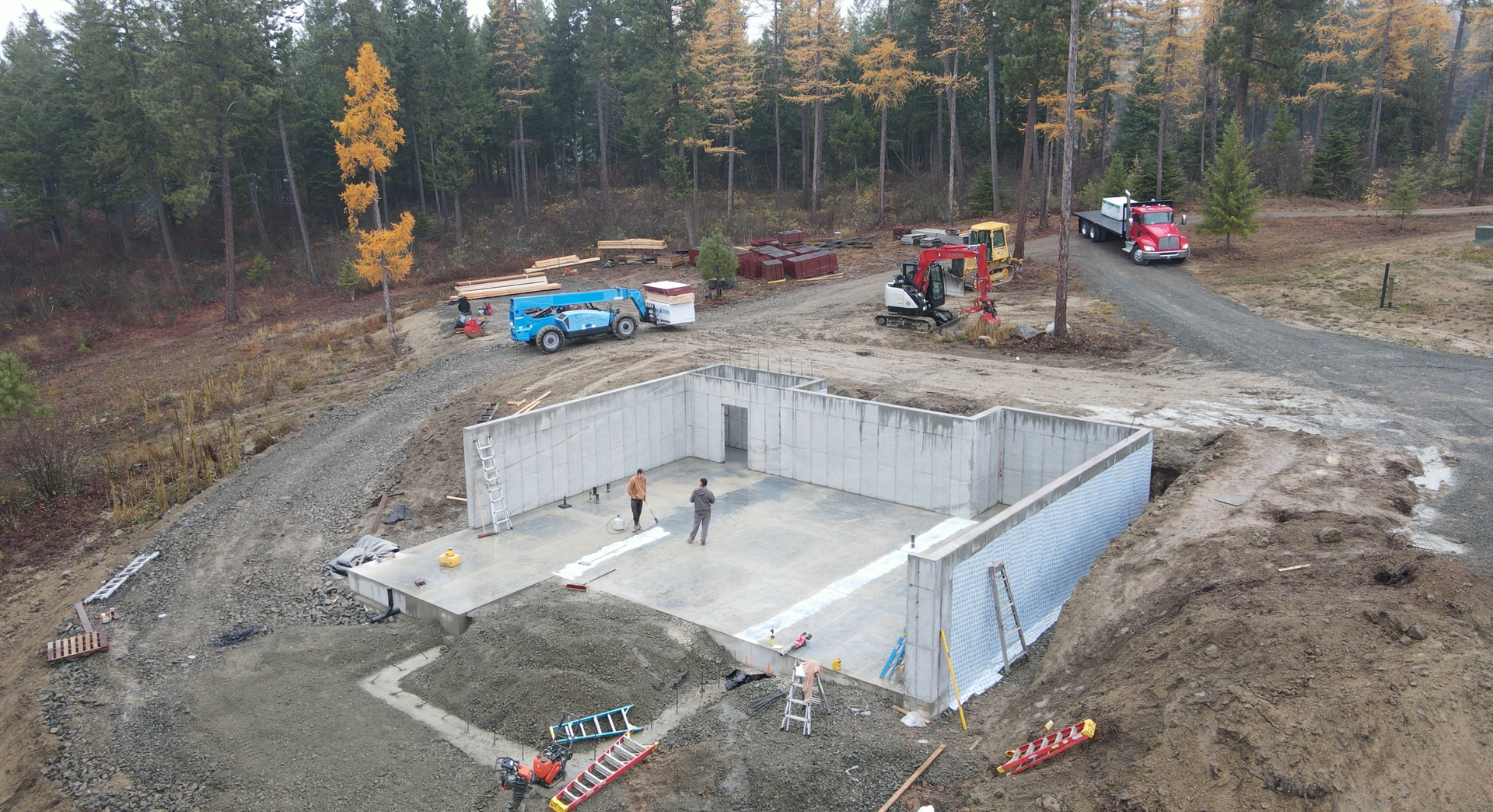 An aerial view of a building under construction in the middle of a forest. Project done by Raise the Bar Construction