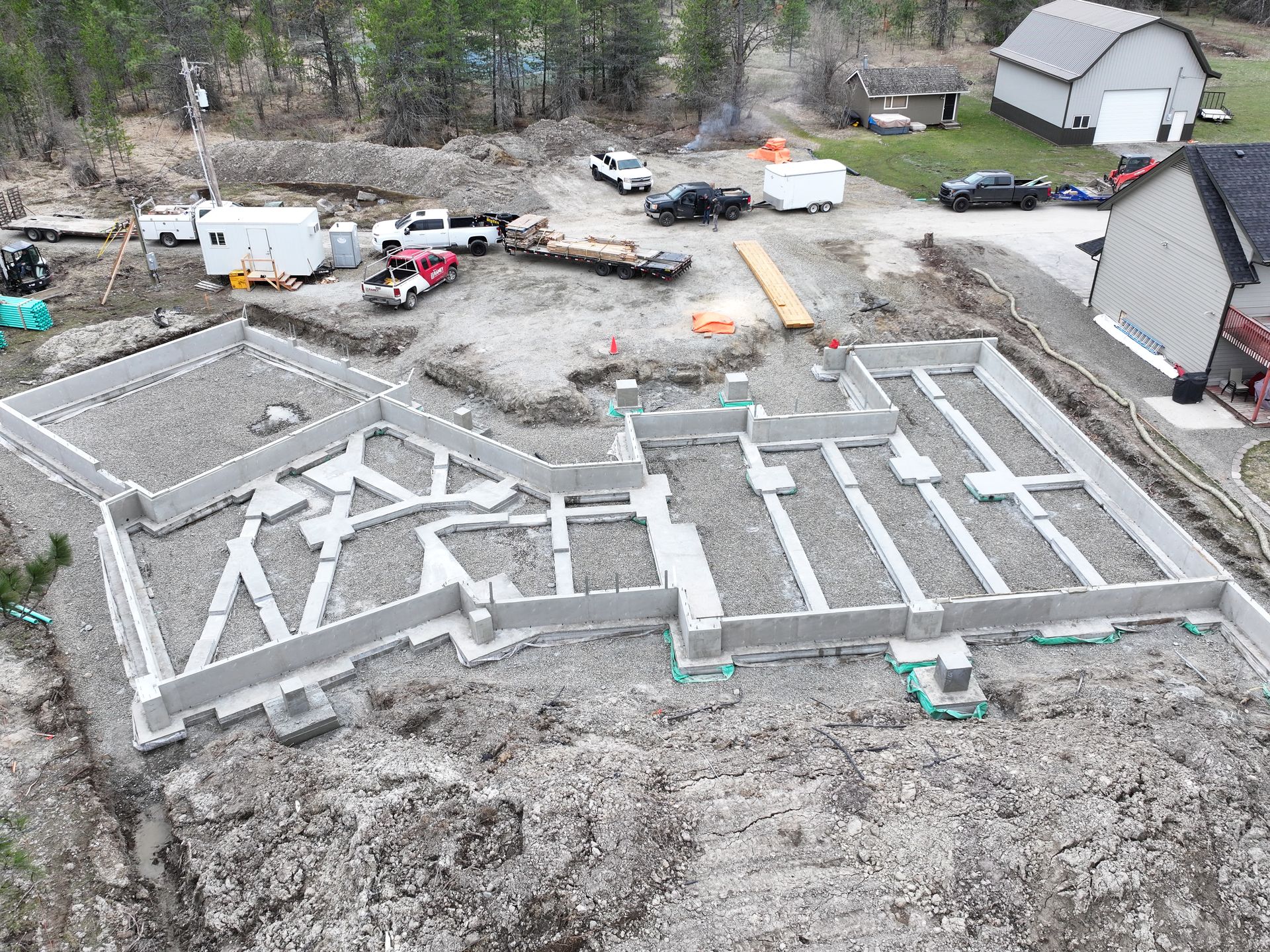 An aerial view of a house under construction in the middle of a dirt field. Project done by Raise the Bar Construction