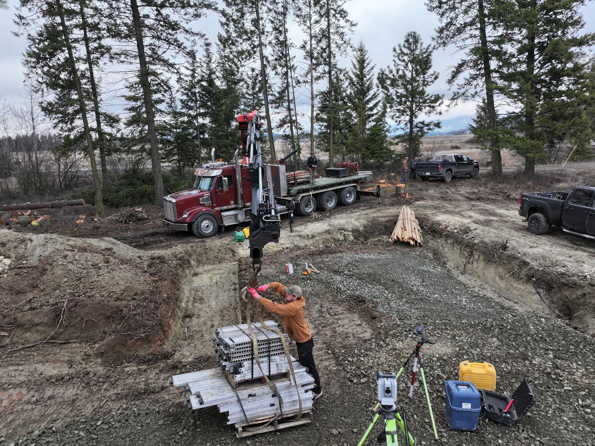 A man is standing next to a truck in a dirt field. Project done by Raise the Bar Construction