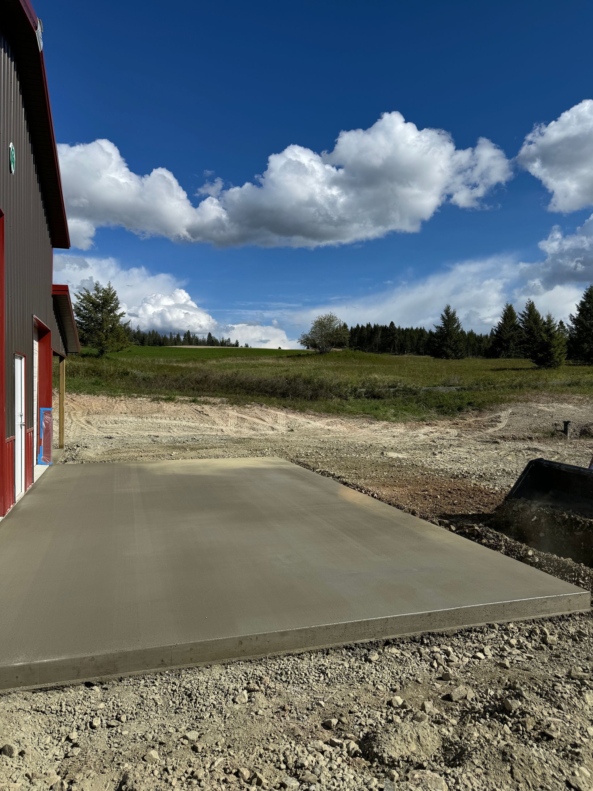A concrete driveway is being built in front of a building. Project done by Raise the Bar Construction