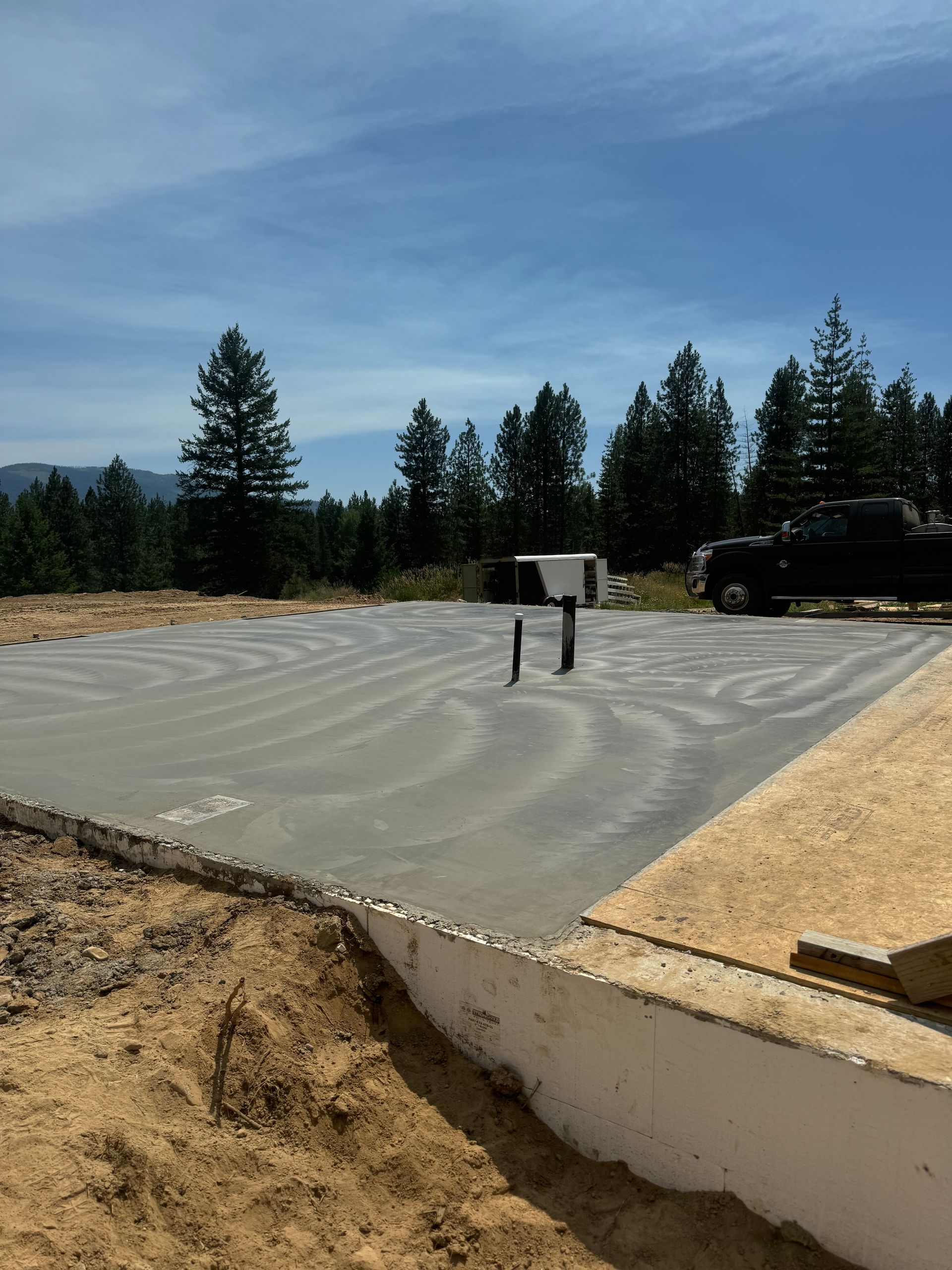 A truck is parked on the side of a concrete foundation. Project done by Raise the Bar Construction