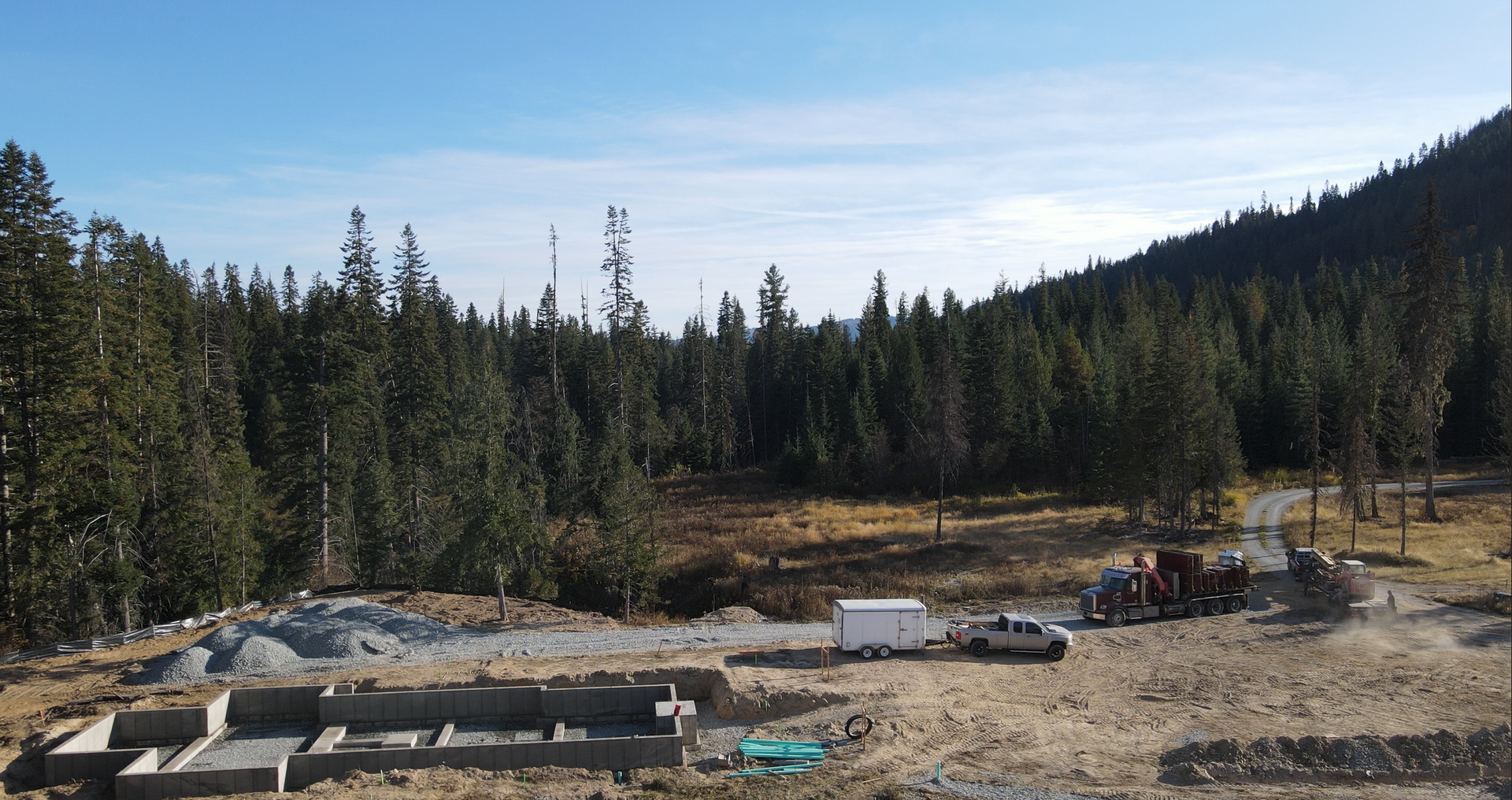 An aerial view of a construction site in the middle of a forest. Project done by Raise the Bar Construction