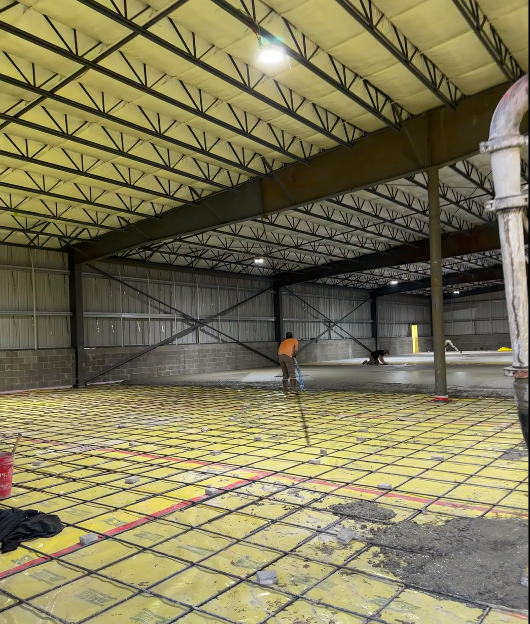 A man is working on the floor of a large building. Project done by Raise the Bar Construction