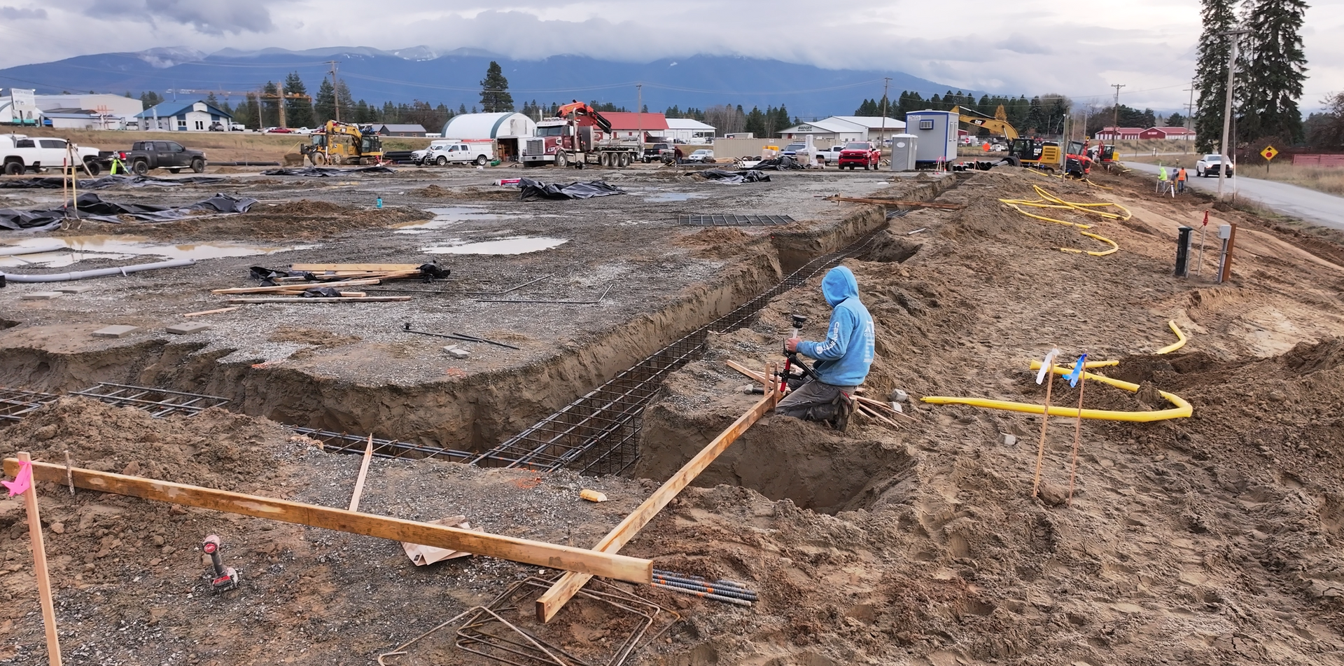 A man is kneeling in the dirt at a construction site. Done by Raise the Bar Construction 