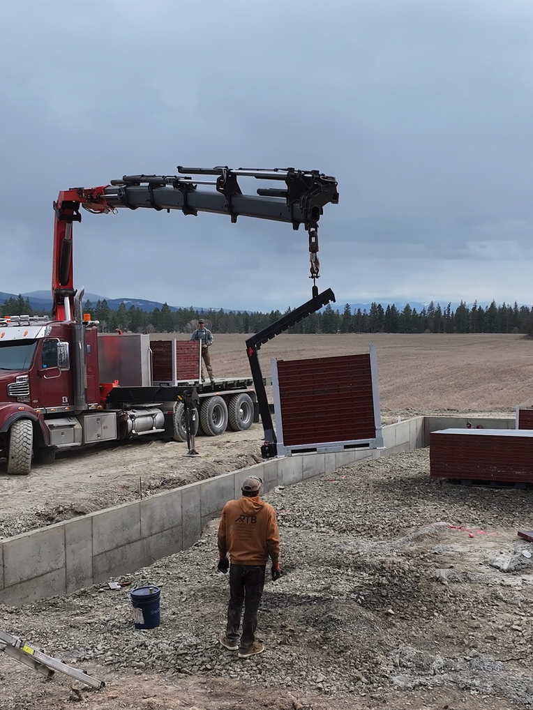 An empty barn with a concrete floor and a wooden roof. Project done by Raise the Bar Construction