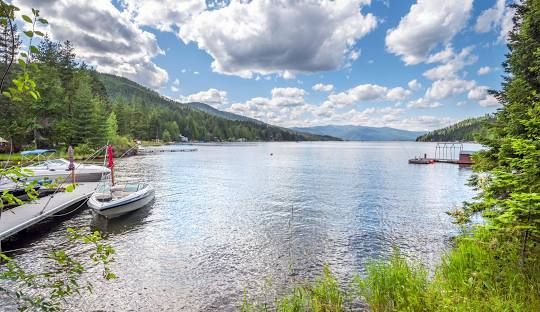 A boat is docked at a dock on a lake with mountains in the background.
