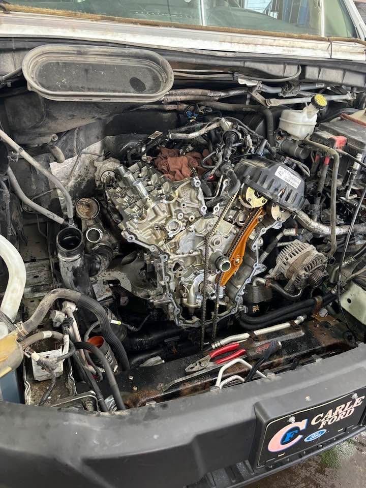 Un homme travaille sous une voiture avec un téléphone à la main