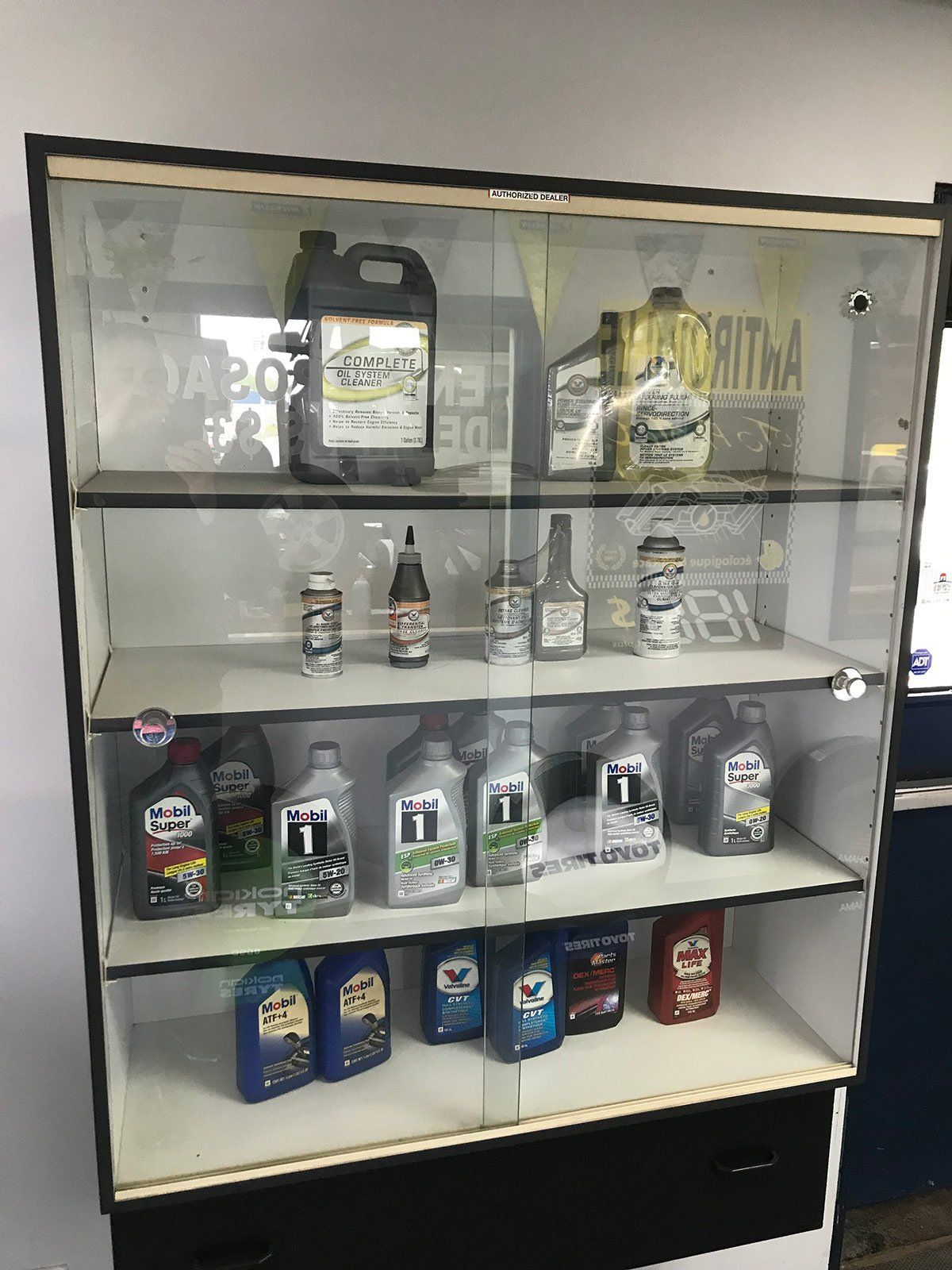 Une vitrine en verre remplie de nombreuses bouteilles d'huile.