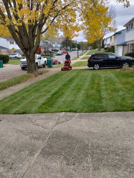 A man is riding a lawn mower on a lush green lawn.