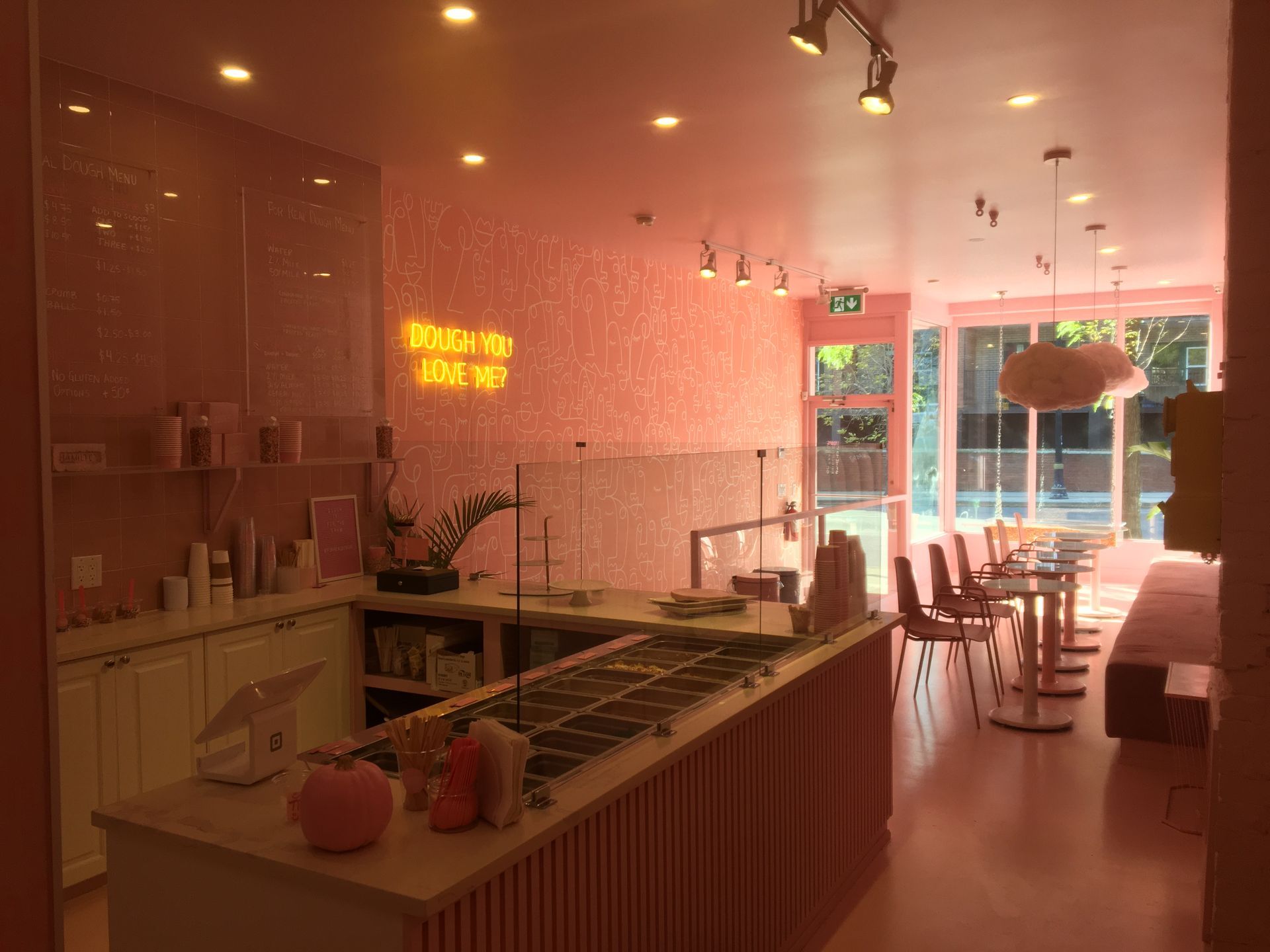 A restaurant with pink walls and a neon sign that says drink me.