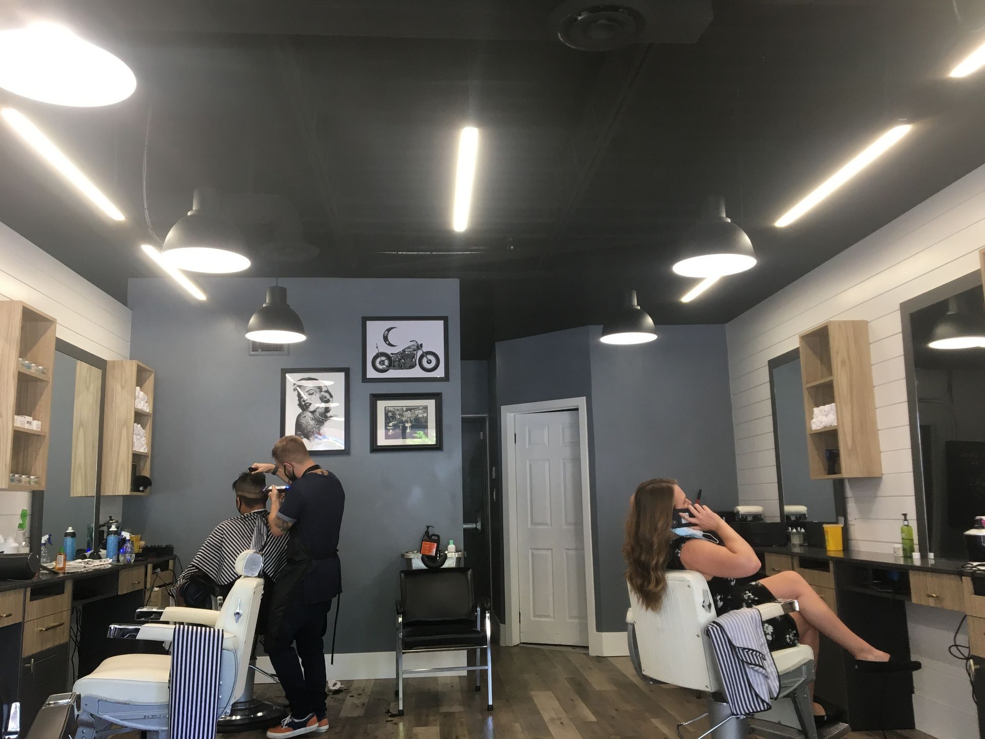 A woman is getting her hair cut in a barber shop.