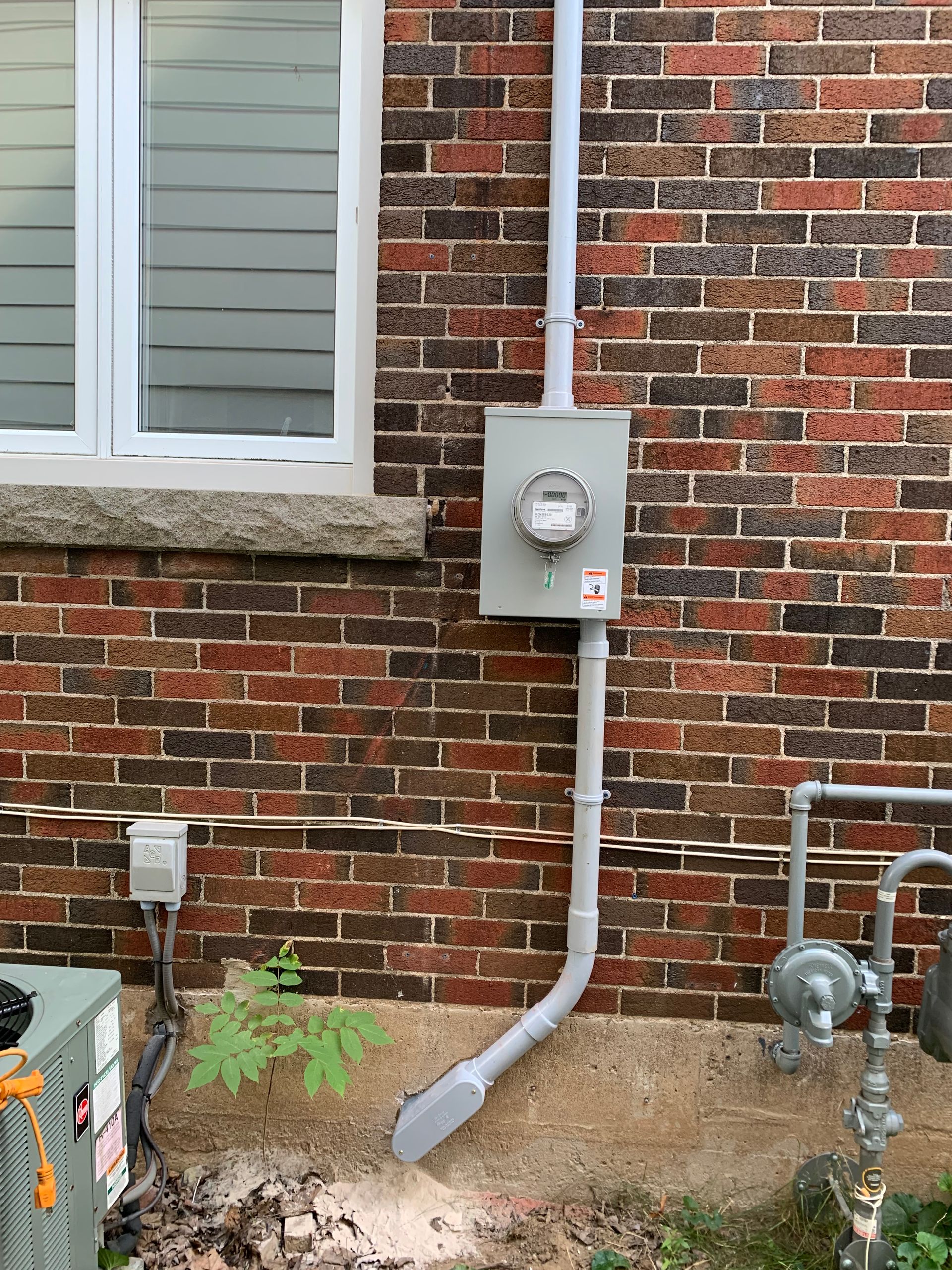 There is a meter on the side of a brick building.