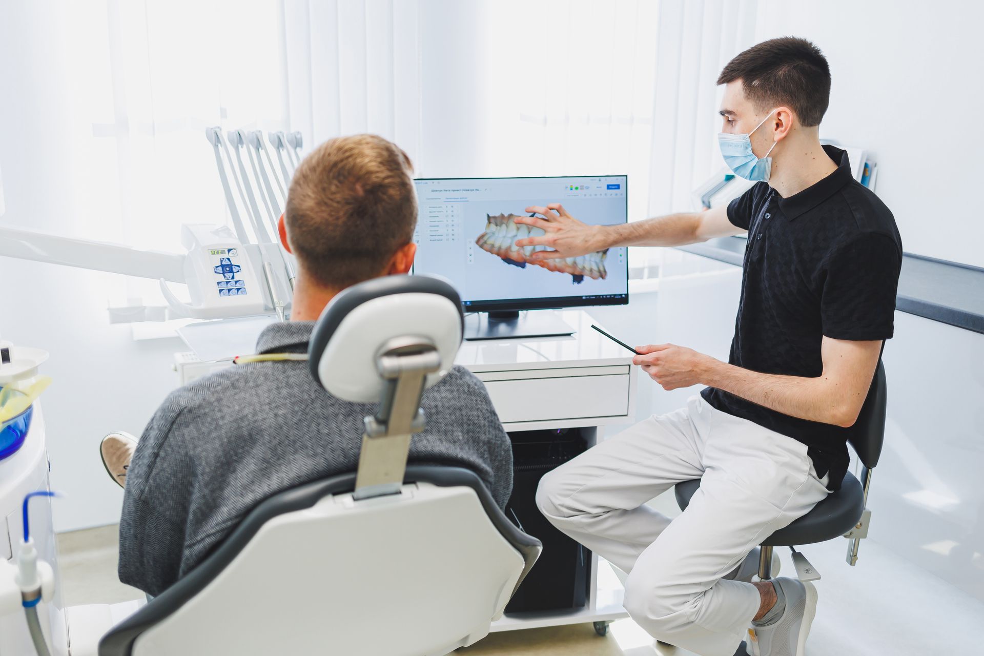 Dentist reviewing 3D dental scan with patient to determine root canal or tooth extraction treatment