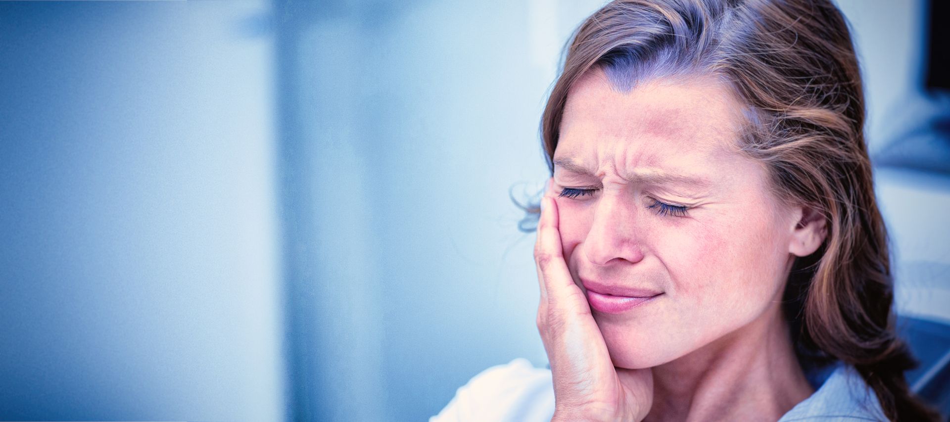Woman holding jaw in pain from severe toothache, showing discomfort from dental emergency