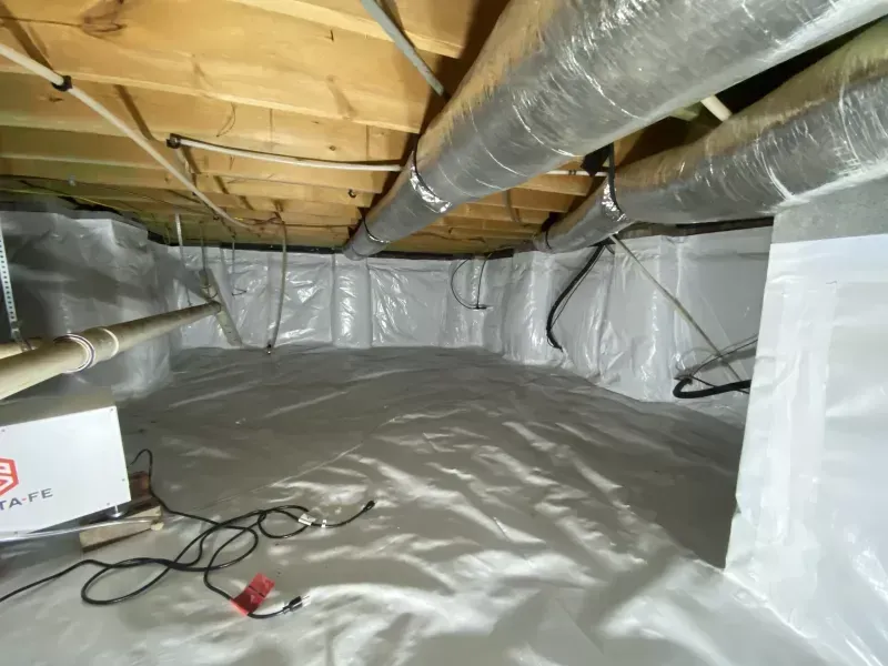 Encapsulated crawl space with white vapor barrier, ducts, and electrical wiring.