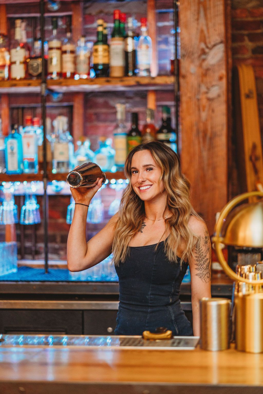 Bartender smiles while shaking a cocktail shaker at a bar.