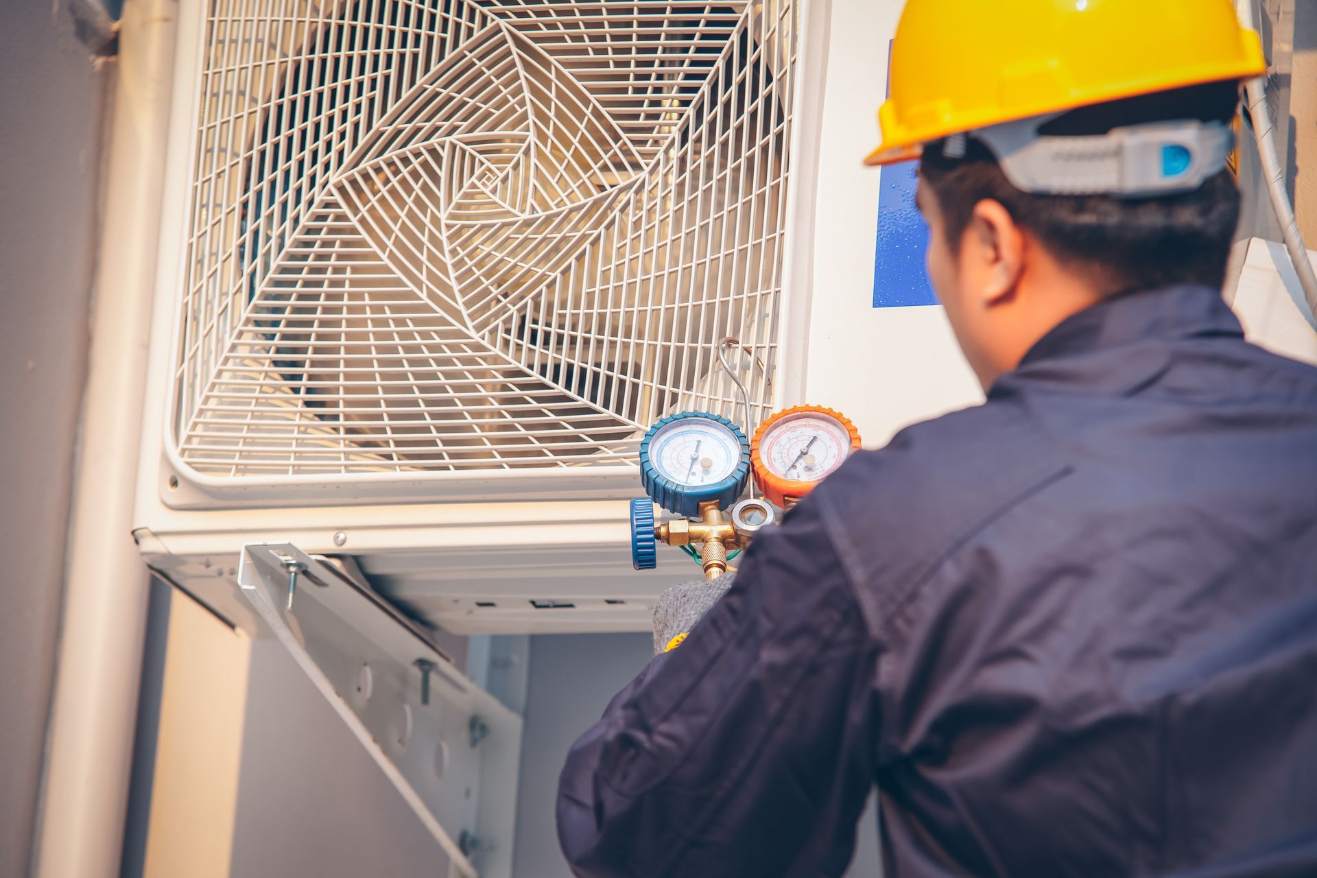 AC technician performing air conditioning maintenance on a wall-mounted outdoor unit in Dallas, wearing safety gear and using pressure gauges