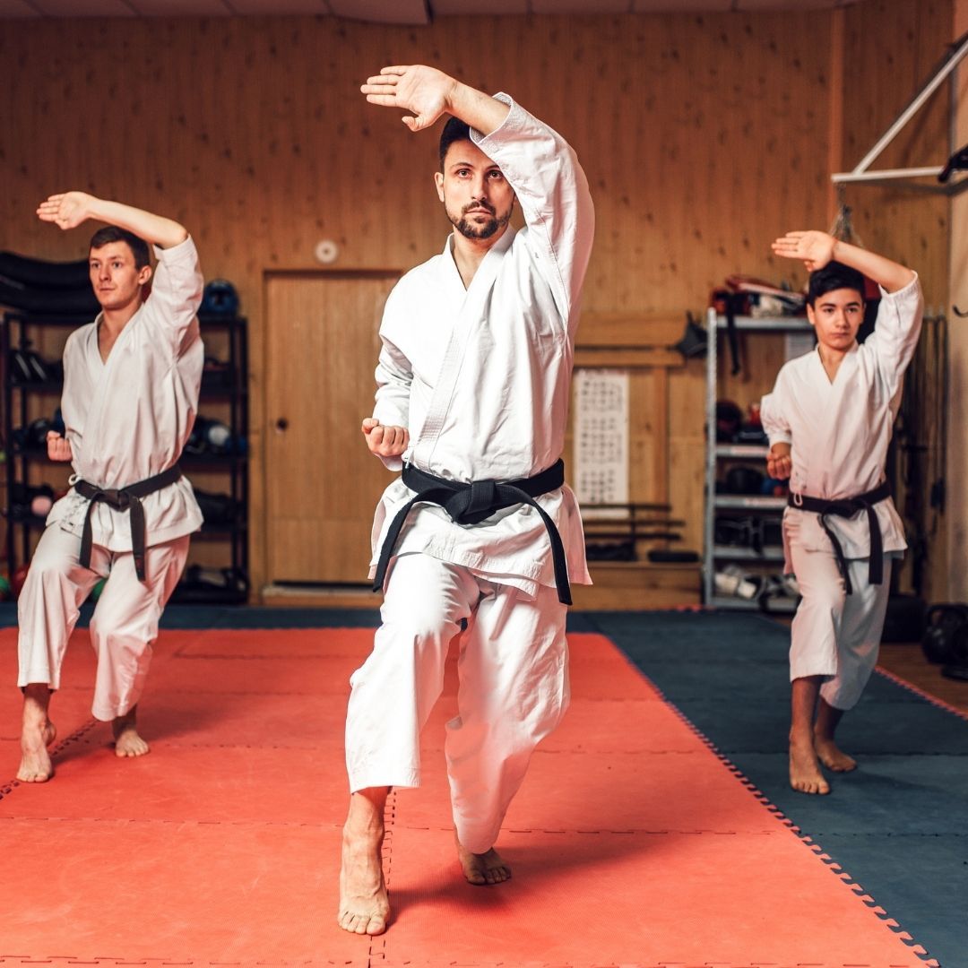 A group of men are practicing karate in a gym.