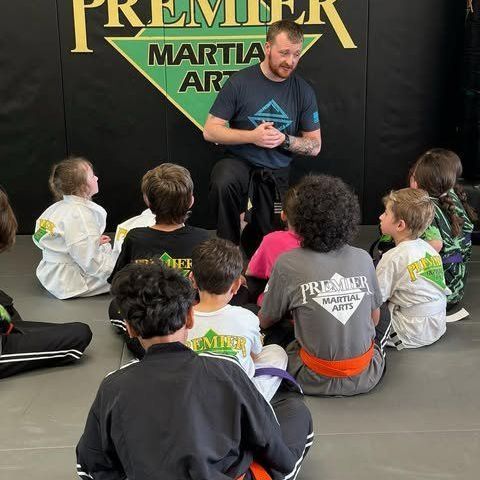 A group of young children in karate uniforms are posing for a picture.