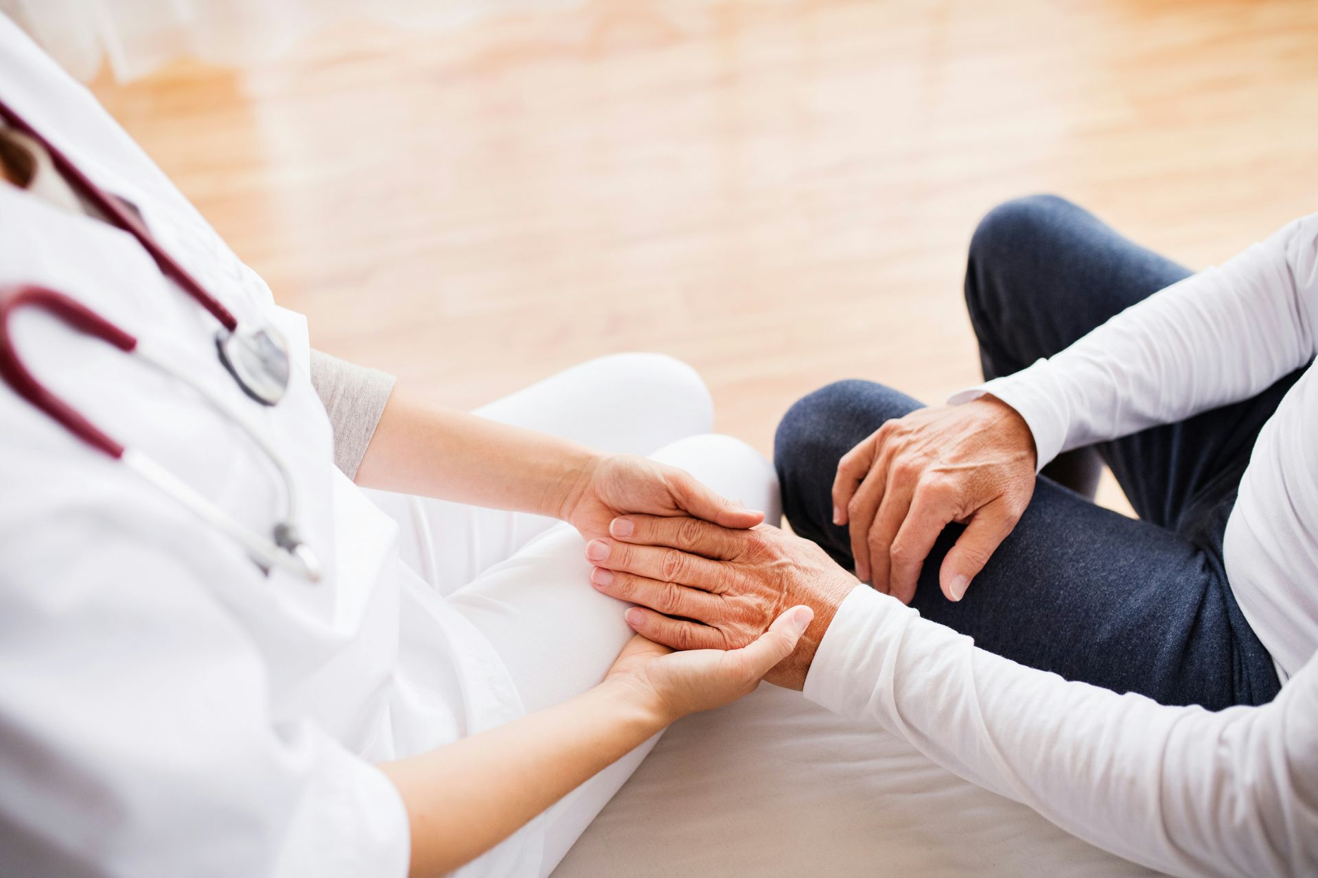 A nurse is holding the hand of an elderly woman.