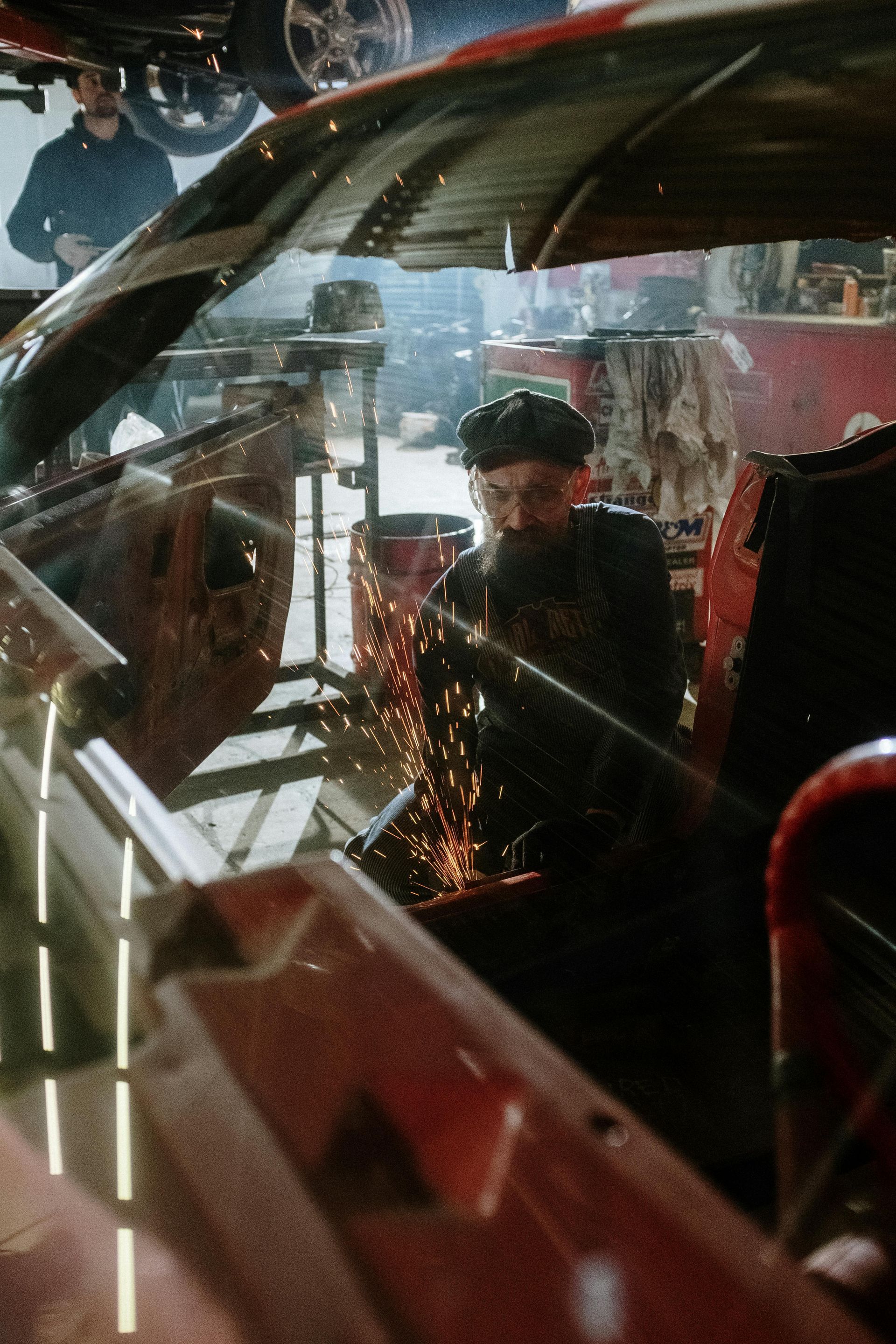 A man is welding a car in a garage.