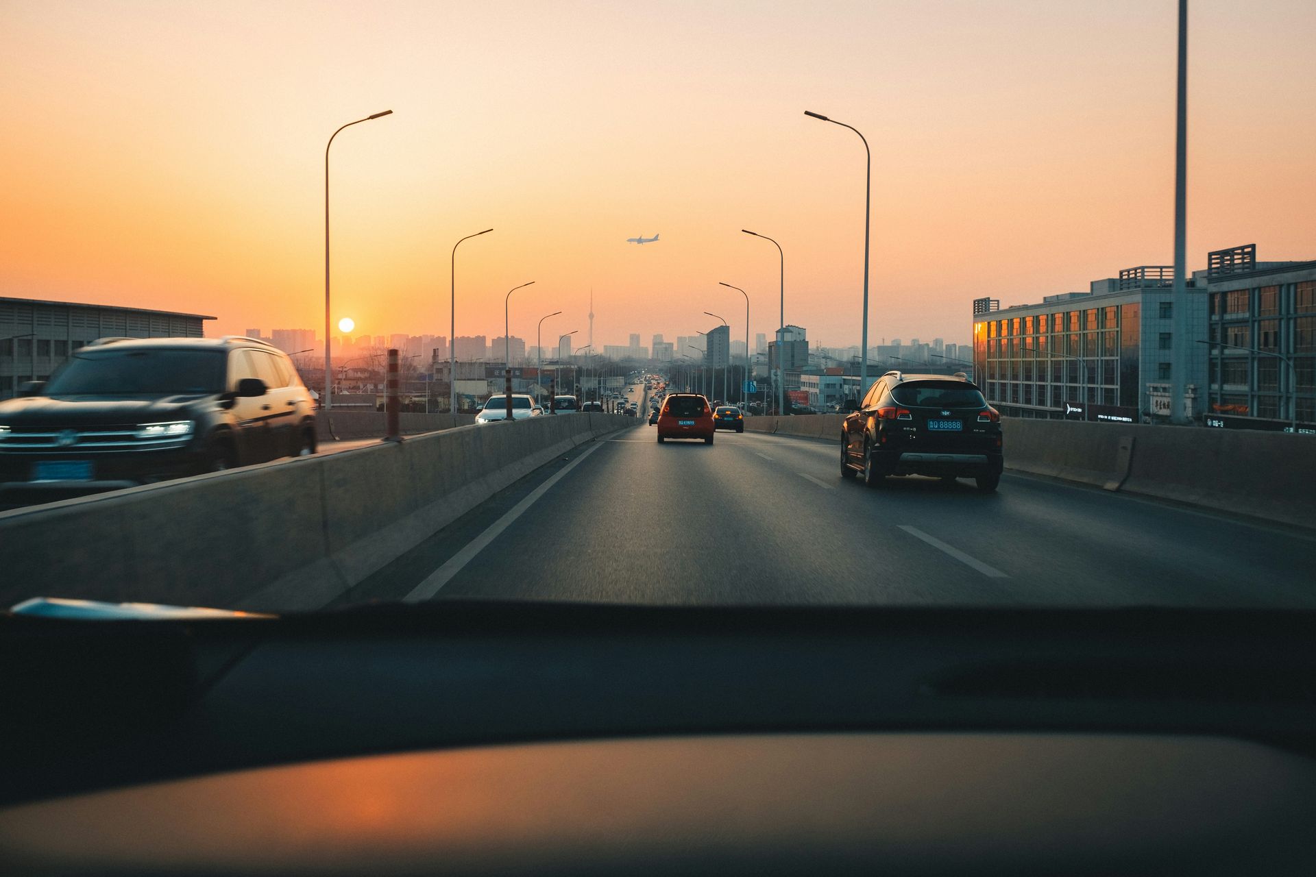 A car is driving down a highway at sunset.