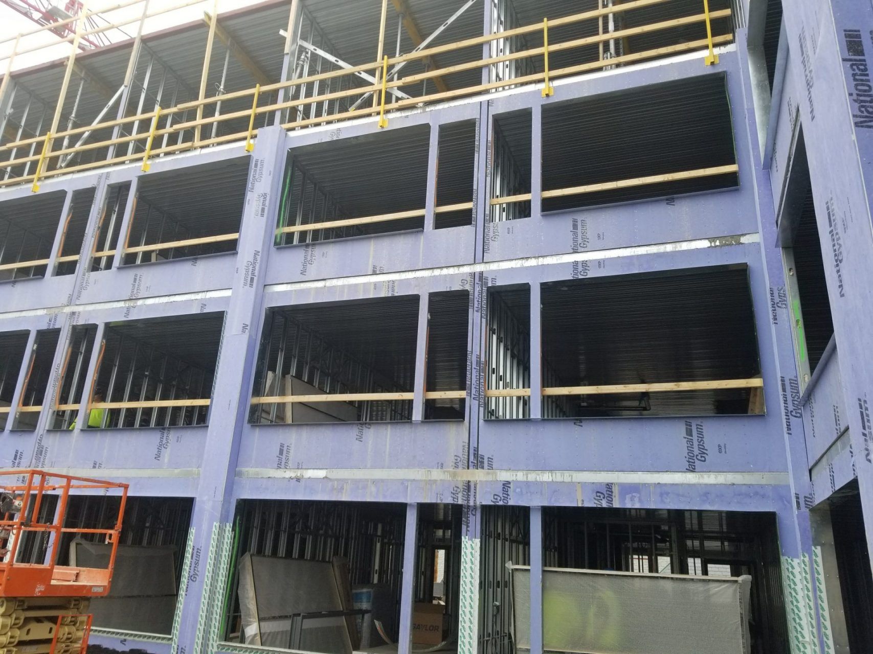 A large building under construction with a scaffolding platform in front of it.