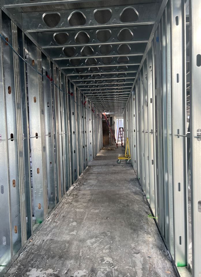 A long metal hallway with a yellow cart in the middle of it.