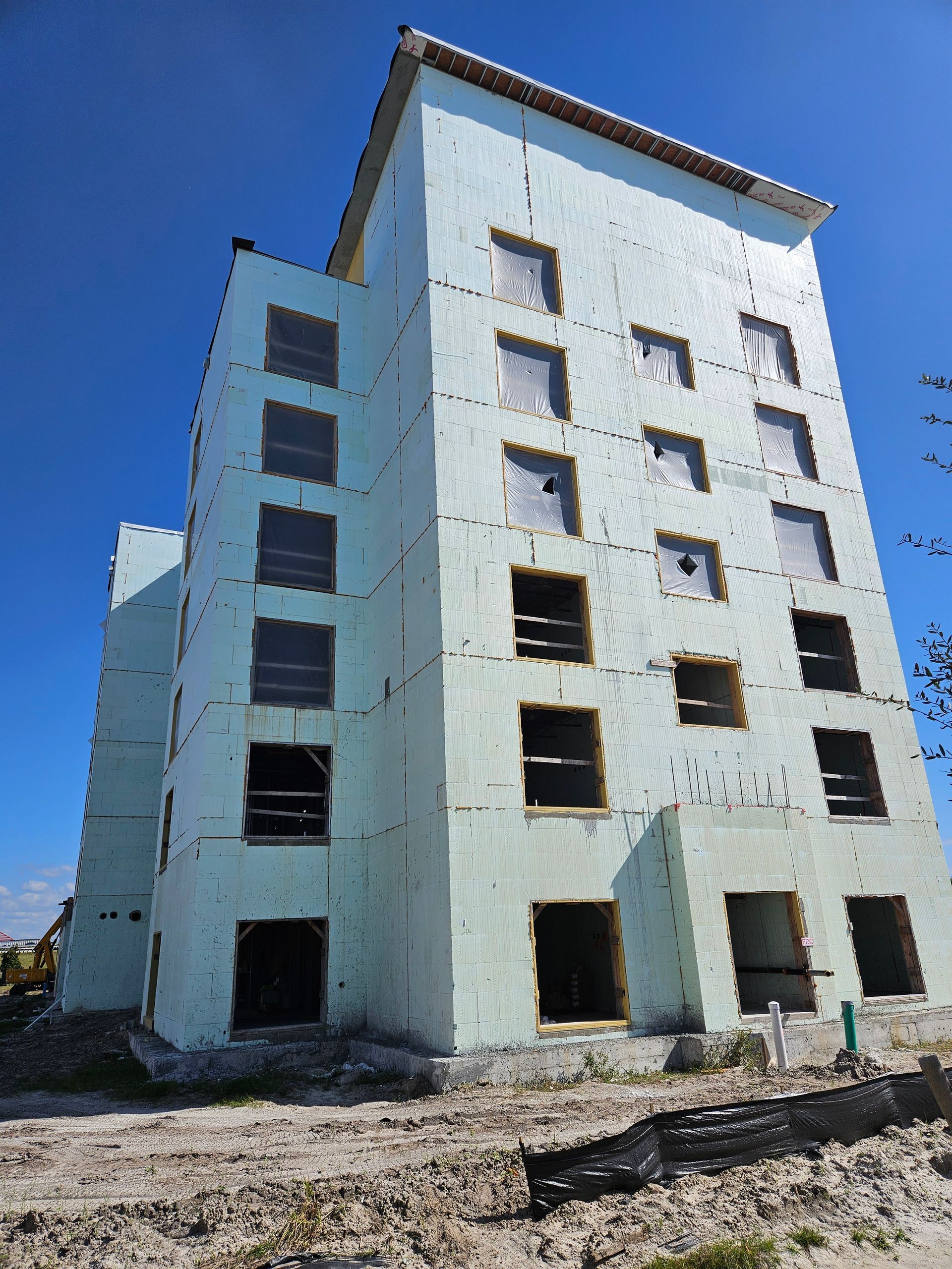 A tall building being constructed and a blue sky in the background.