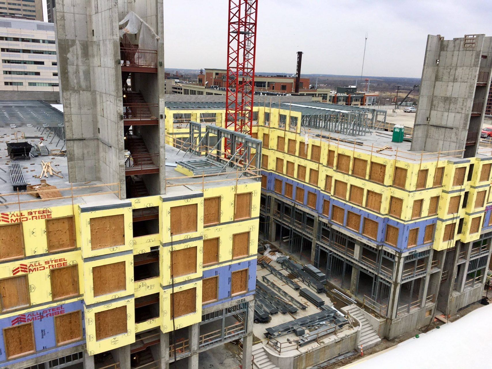 A large building under construction with a red crane in the background.