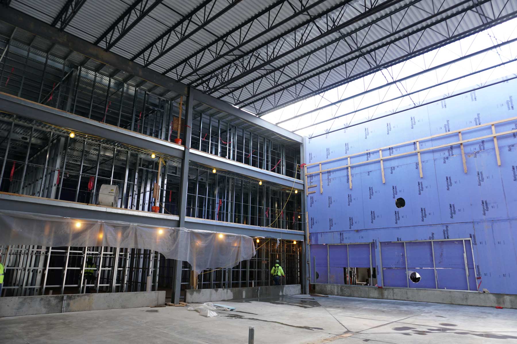 A large building under construction with blue insulation panels.