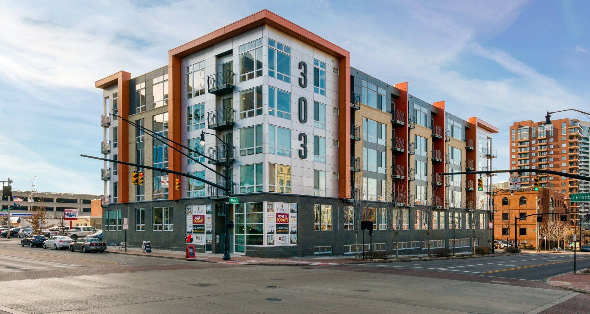 A large building with a lot of windows is sitting on the corner of a city street.