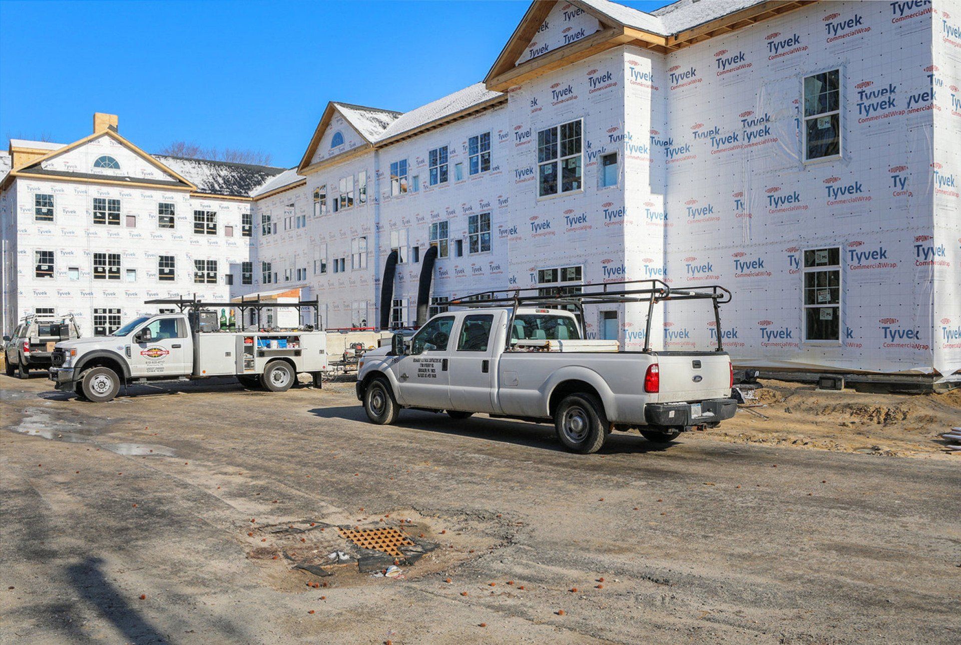 A row of trucks are parked in front of a building under construction.