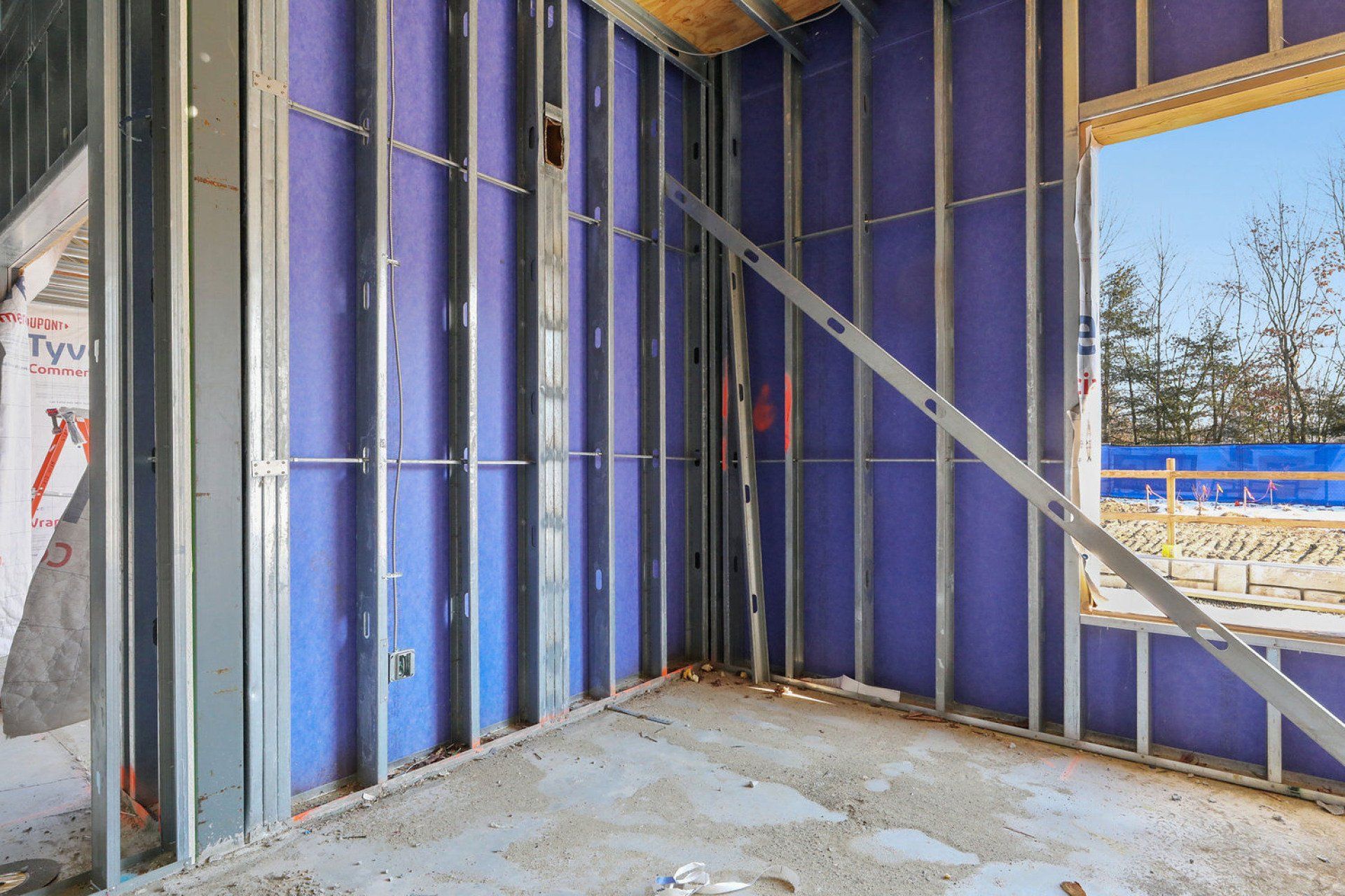 A room in a building under construction with blue walls and a window.