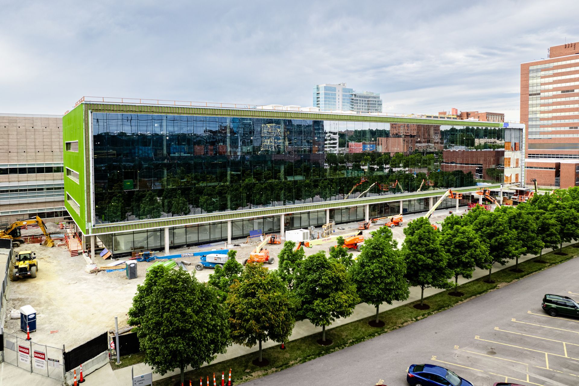 An aerial view of a large building with a green side and windows all across the front.