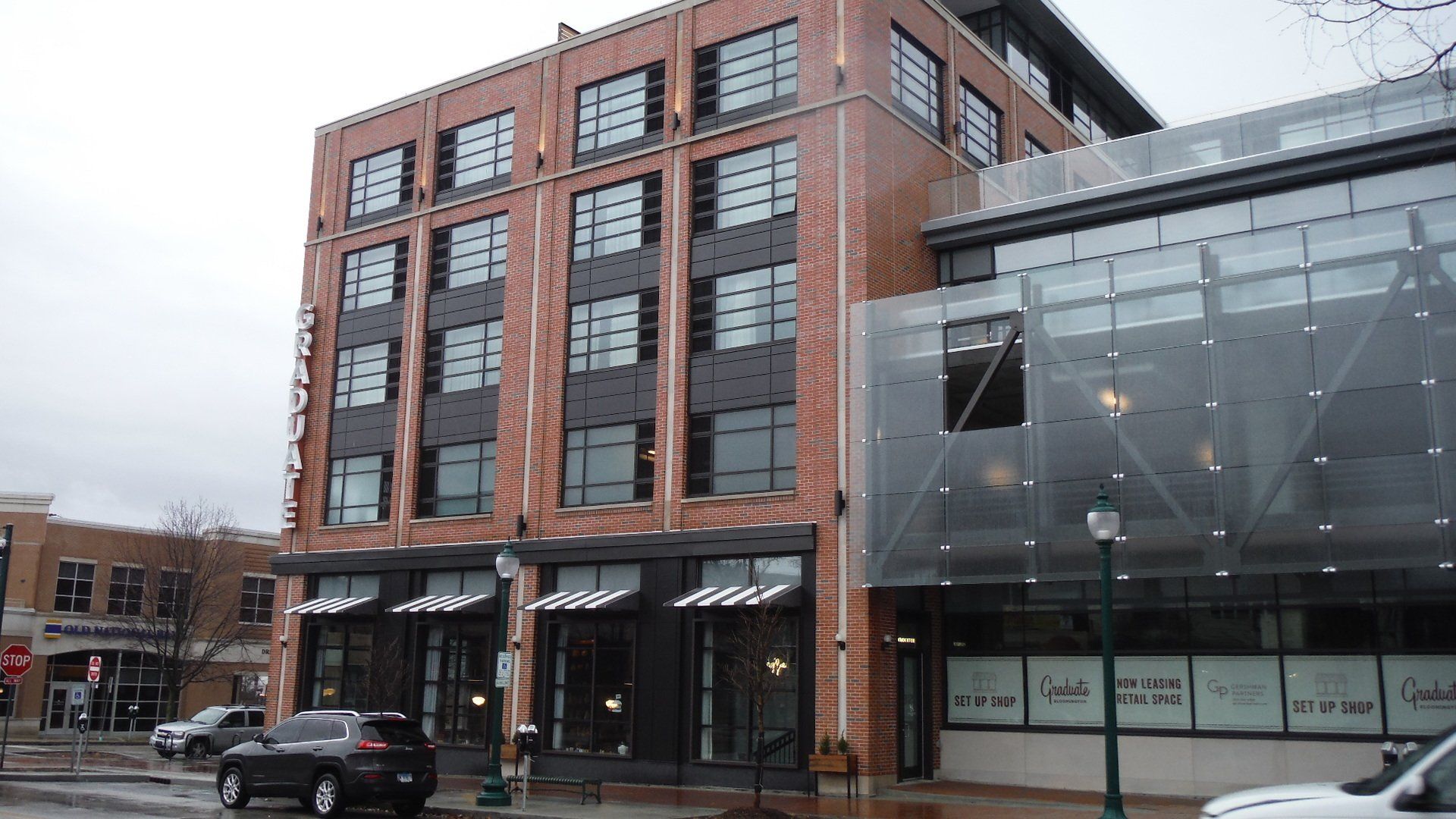 A brick building with a lot of windows and vehicles parked in front of it.