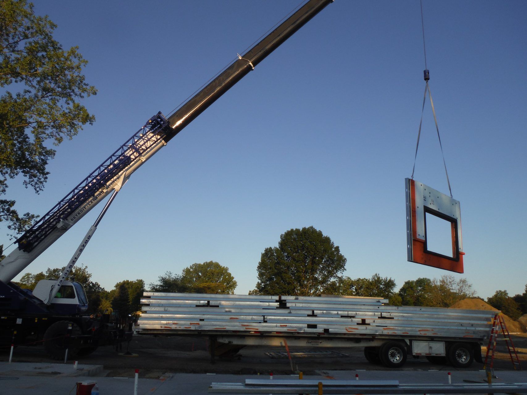 A crane is lifting a piece of metal into the air.
