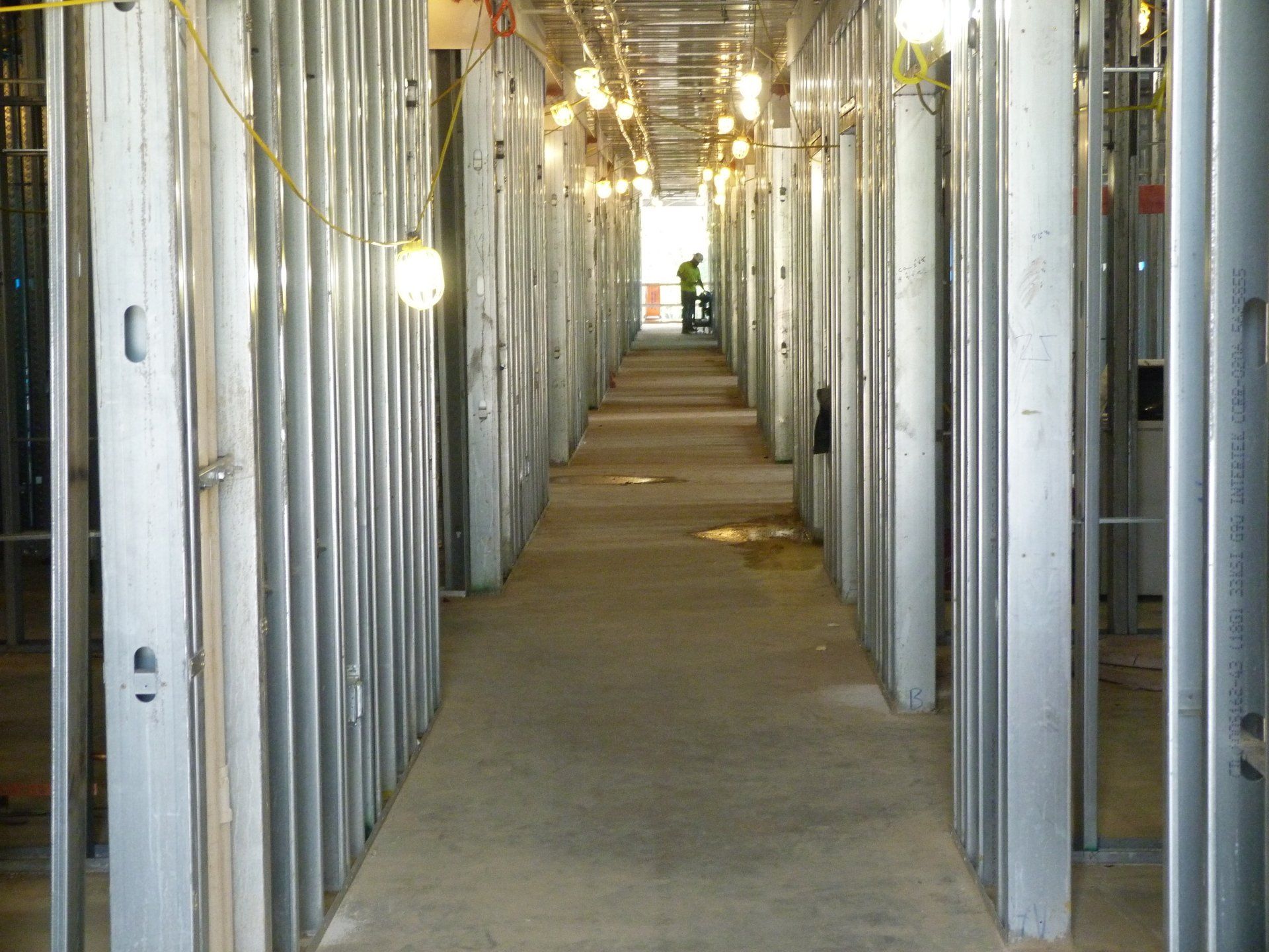 A long hallway with steel beams and a few lights hanging from the ceiling.