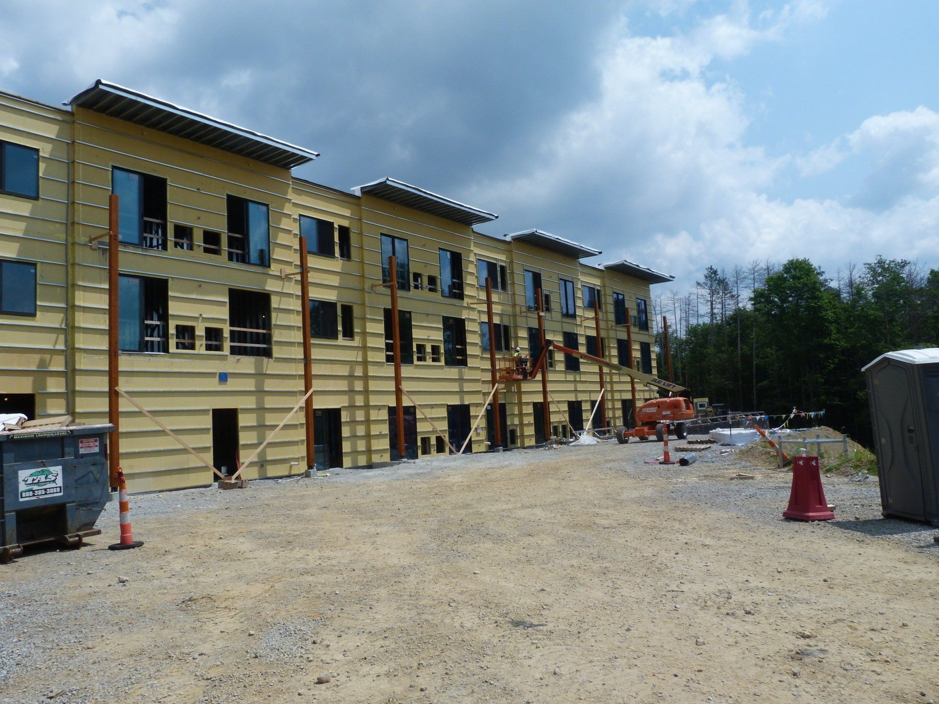 A building under construction with a dumpster in front of it. 