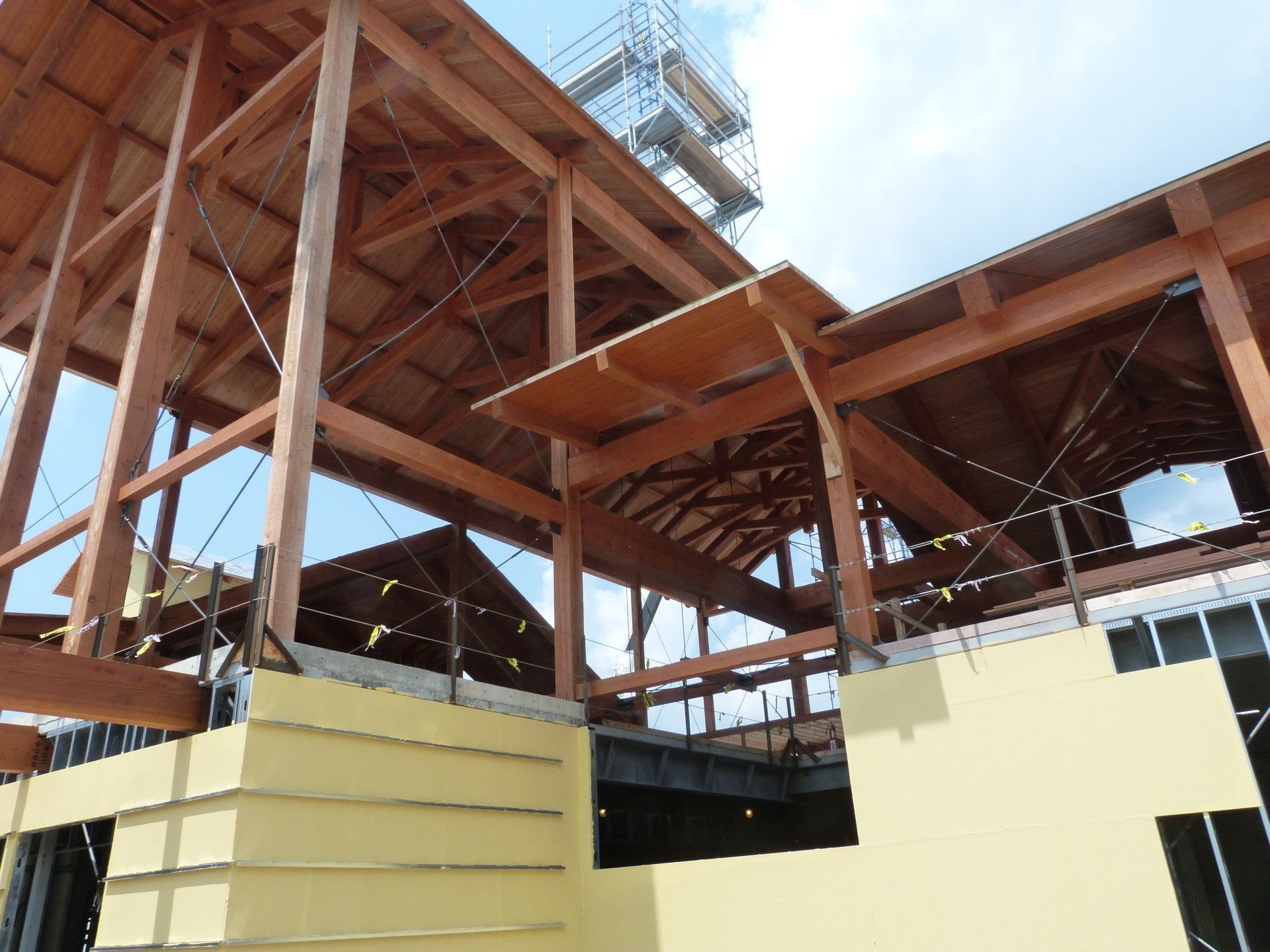 A building under construction with wooden beams and a yellow wall.
