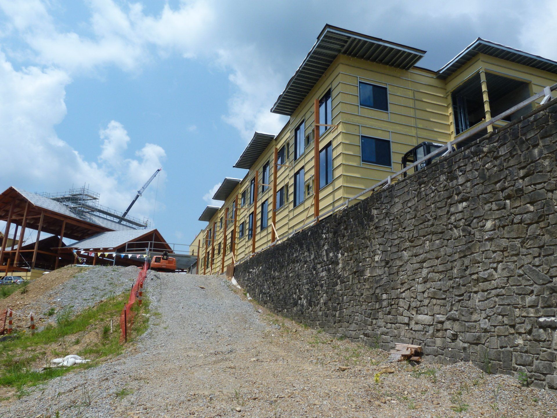 A large building is being built on a hill next to a stone wall.