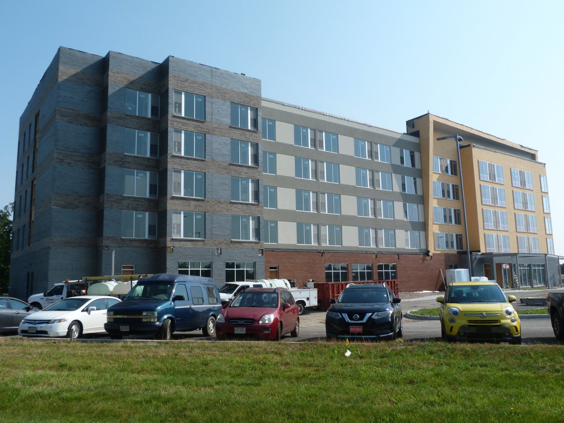 A row of cars are parked in front of a large building.