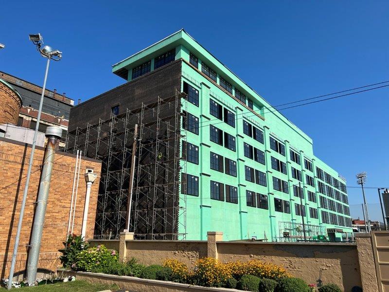 A large green building with a lot of windows is being built.