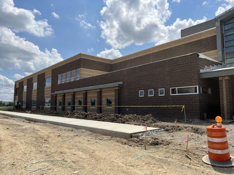 A large brick building is being constructed with dirt surrounding.