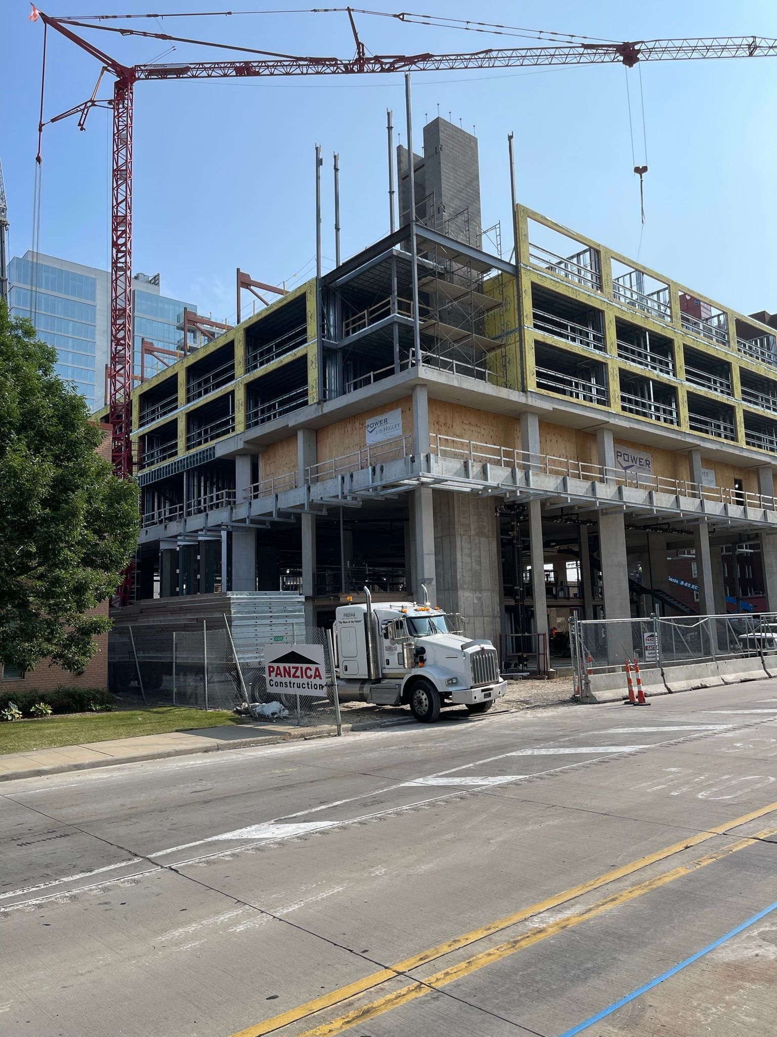 A white truck is parked in front of a large building under construction