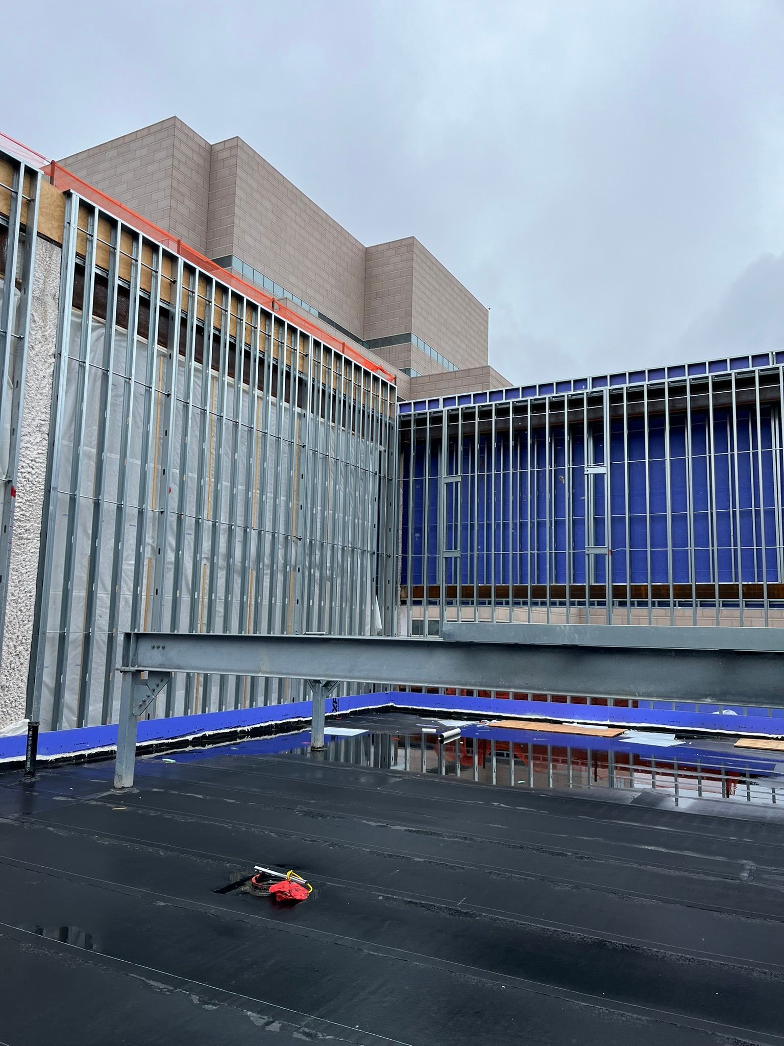 A large building under construction with a blue curtain behind it.